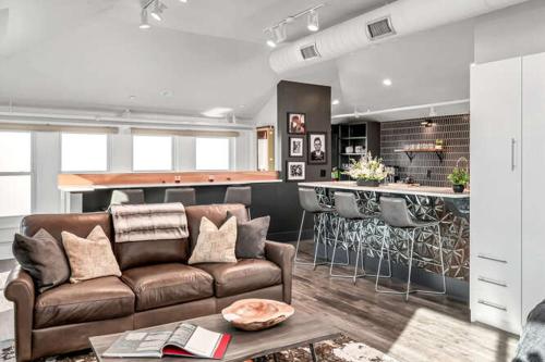 a living room with a brown couch and a kitchen at Skyline Suite with Penthouse & Rooftop Deck in Nashville