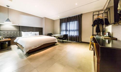 ソウルにあるYeongdeungpo Lifestyle F Hotelのベッドとデスクが備わる広い客室です。