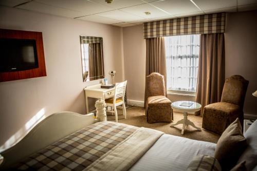 a hotel room with a bed and a desk and chairs at Best Western Plus West Retford Hotel in Retford