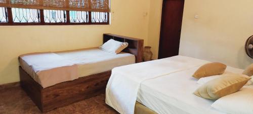 a bedroom with two beds and a window at The Villa Marcelle in Negombo