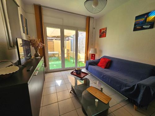un salon avec un canapé bleu et une table dans l'établissement Charmant T2 à Saint-Cyprien - Terrasse, Clim, Proche Plage et Parking Privé - FR-1-309-444, à Saint-Cyprien