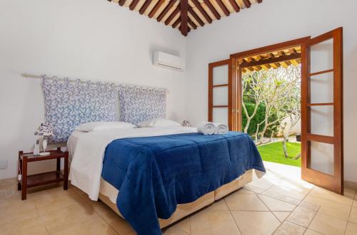 a bedroom with a bed with a blue and white bedspread at Casa Sol Búzios in Armacao dos Buzios