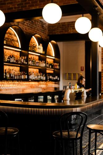 a woman sitting at a bar in a restaurant at The Victoria Hotel Rutherglen in Rutherglen