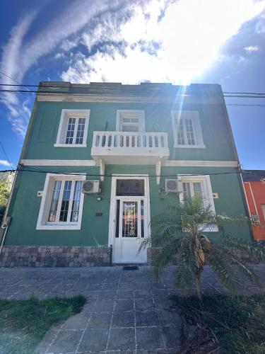 een groen huis met een witte deur en een palmboom bij Incantare ApartHotel in Piriápolis
