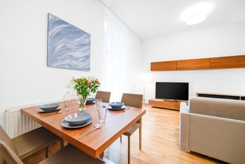 a dining room with a wooden table and a television at Bishop Apartments in Brno