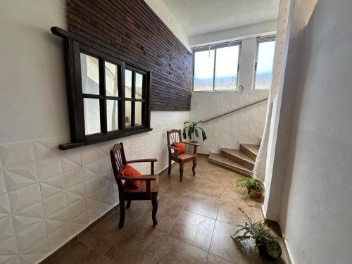 een hal met 2 stoelen, een tafel en een trap bij Incantare ApartHotel in Piriápolis