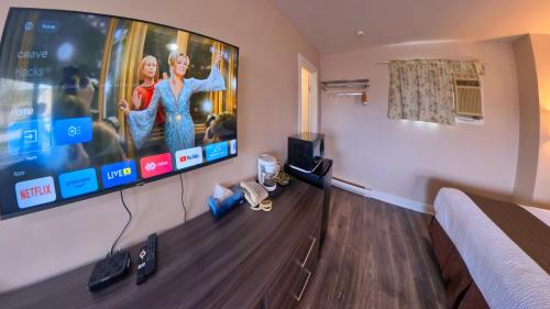 a hotel room with a tv on a wall at Maple Leaf Inn & Suites in Kincardine