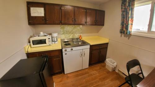 a small kitchen with a sink and a microwave at Maple Leaf Inn & Suites in Kincardine