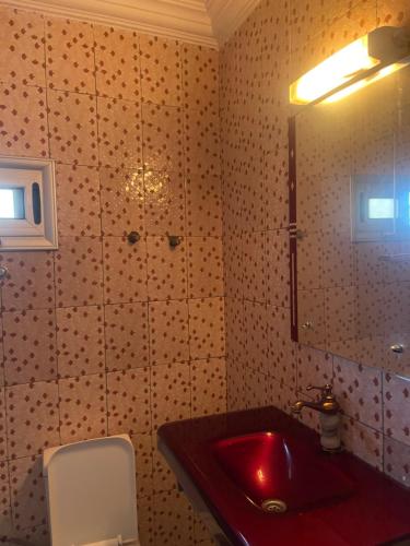 ein Badezimmer mit einem roten Waschbecken und einem Spiegel in der Unterkunft RÉSIDENCE ACHIKA INELIA in Bobo-Dioulasso
