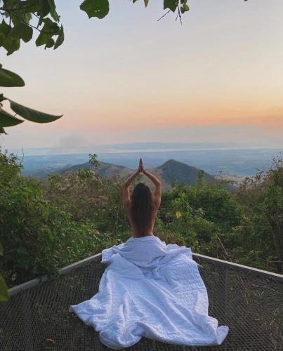 a person sitting on top of a mountain looking at the horizon at Domos Mirador Romantic Private Honeymoon Glamping in Miramar