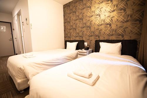 two beds in a hotel room with towels on them at アナザースカイ京都二条城 in Kinugasa