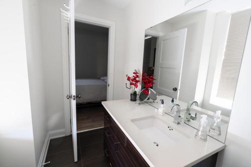 a white bathroom with a sink and a mirror at Spacious 3 Bedroom Apartment in Heart of Niagara in Thorold