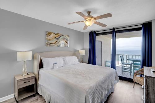 a bedroom with a bed with a ceiling fan and a balcony at Windward Pointe 706 in Orange Beach