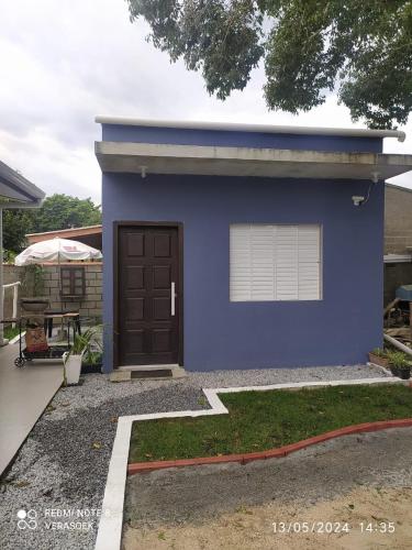 a blue house with a brown door in a yard at Kitnet privada confortável em Pontal do Sul in Pontal do Paraná