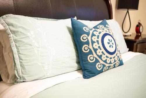 a bed with a blue and white pillow on it at Spacious 3 Bedroom Apartment in Heart of Niagara in Thorold