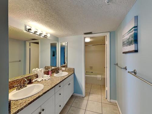 a bathroom with two sinks and a large mirror at Ocean Sands 1002 in St. Pete Beach