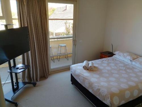a bedroom with a bed and a large window at Lovely 2 bedroom apartment across from Shepp Lake. in Shepparton