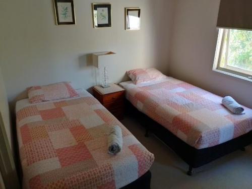 a bedroom with two beds and a cat laying on the bed at Lovely 2 BR Spa apartment, Opposite Shepp Lake in Shepparton