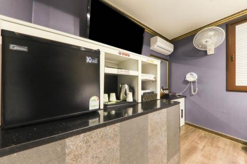 cocina con TV de pantalla plana grande en Nobless Motel, en Sin-ni