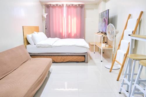 um pequeno quarto com uma cama e um sofá em QFandZ Baguio Homestay at BRENTHILL Condominium em Baguio
