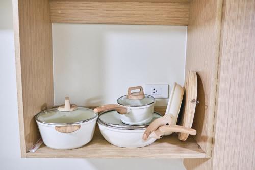 three pots and pans on a shelf in a cabinet at QFandZ Baguio Homestay at BRENTHILL Condominium in Baguio