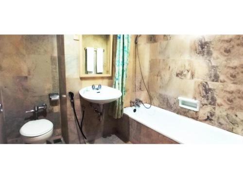 een badkamer met een wastafel, een toilet en een bad bij Merpati Hotel in Pontianak