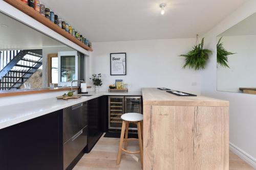 a kitchen with a wooden counter and a stool at Reflections at Sunset Beach in Soldiers Point
