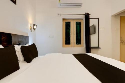 um quarto com uma grande cama branca com almofadas pretas em CASA INN em Varanasi