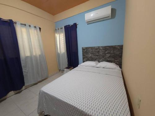 a bedroom with a white bed and a blue wall at Casa & Alojamiento La Roca in Puerto Cortes