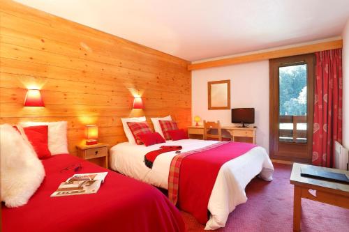 two beds in a room with wooden walls at Hôtel du Bourg in Valmorel