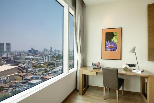 an office with a desk and a large window at Eastin Grand Hotel Sathorn in Bangkok