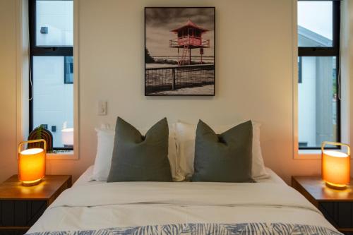 a bedroom with a bed with two lamps and two windows at Sunsoaked seaside 1 bedroom 1 bath in Christchurch