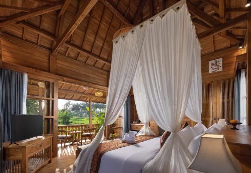 una camera con letto a baldacchino bianco di The Kalyana Ubud Resort ad Ubud