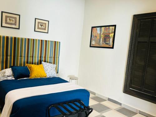 een slaapkamer met een bed met blauwe en gele kussens bij Hotel Boutique Casona los Pavorreales in Durango