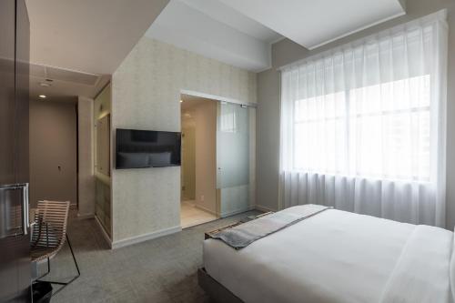 a bedroom with a bed and a tv and a window at Stanton House El Paso in El Paso