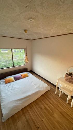 a bedroom with a white bed and a table at Sound Garden Biei, Cricket in Biei
