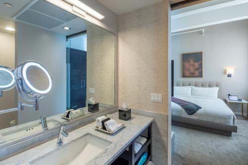 uma casa de banho com um lavatório, um espelho e uma cama em Stanton House El Paso em El Paso