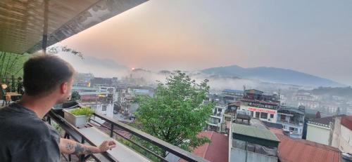 a man standing on a balcony looking at a city at Central Sapa Serenity Homestay in Sa Pa