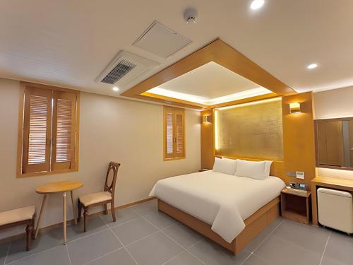 ein Schlafzimmer mit einem Bett, einem Tisch und einem Stuhl in der Unterkunft Sokcho Mir Hotel in Sokcho