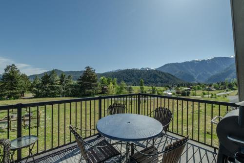 a table and chairs on a balcony with mountains at Berg Haus by NW Comfy Cabins in Leavenworth