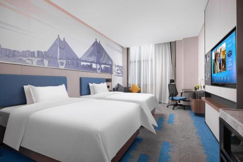 a hotel room with two beds and a flat screen tv at Hampton by Hilton Wuhan Zhongnan Jiedaokou Hotel in Wuhan