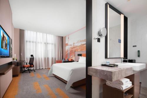 a hotel room with a bed and a sink and a mirror at Hilton Hotel by Hampton Wuhan Zhongnan Street Branch in Wuhan