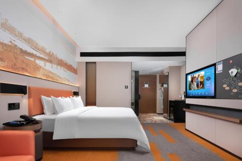a hotel room with a bed and a flat screen tv at Hilton Hotel by Hampton Wuhan Zhongnan Street Branch in Wuhan