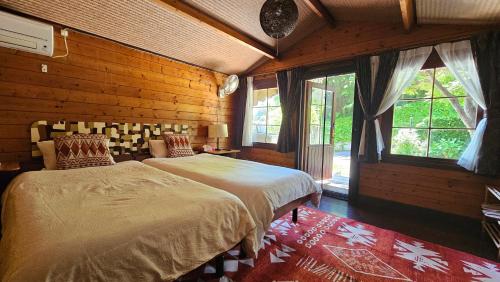 岡山市にあるLoft & Log Houseの木製の壁のベッドルーム1室(ベッド2台付)