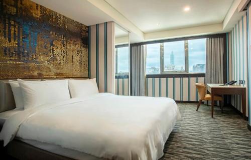 a bedroom with a large white bed and a desk at Hej Taipei Arena Hotel in Taipei