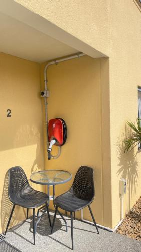 a table and two chairs in front of a wall at Bella Vista Motel Whangarei in Whangarei