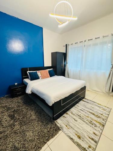 een slaapkamer met een groot bed met een blauwe muur bij Cozy Dala Room in Sharjah
