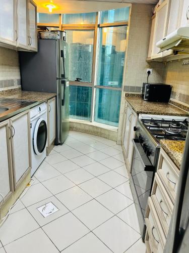 a kitchen with a refrigerator and a washer and dryer at Cozy Dala Room in Sharjah