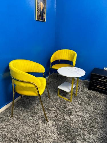 two yellow chairs and a table in a room at Cozy Dala Room in Sharjah