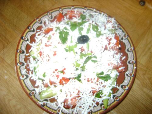 a pizza on a plate on a table at Guest House Todorini kashti in Koprivshtitsa